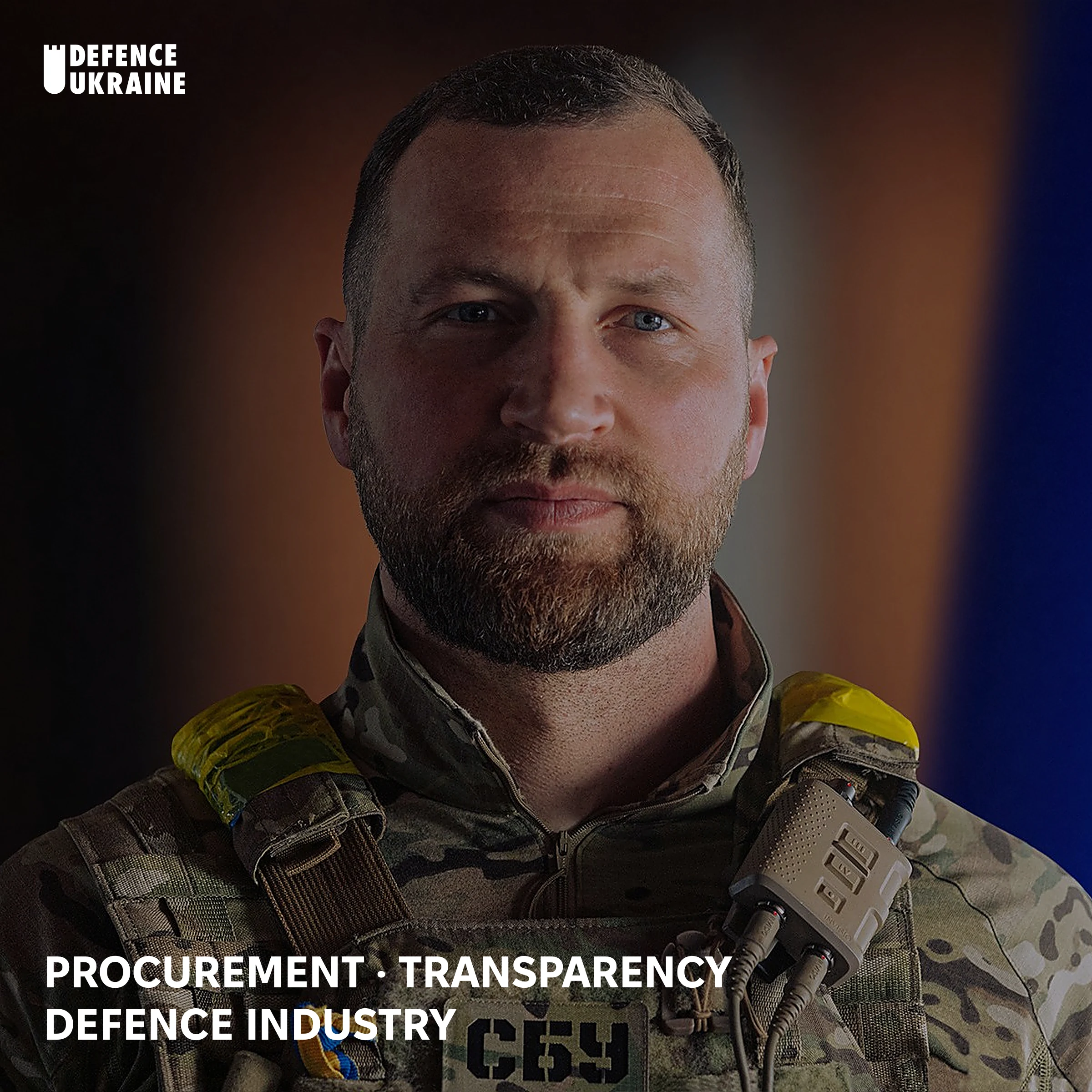 Yevhenii Khmara, Ukraine's acting Defence Minister and former Security Service officer, in camouflage and body armour with an SBU patch, standing before a Ukrainian flag in an official state portrait.